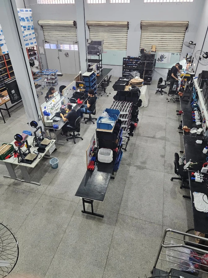 Vista real da fábrica Allcanci em Betim, com equipe e bancadas de produção